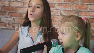 两个小女孩正对着麦克风唱歌。 家里卡拉OK里的歌。 4k，慢镜头，特写